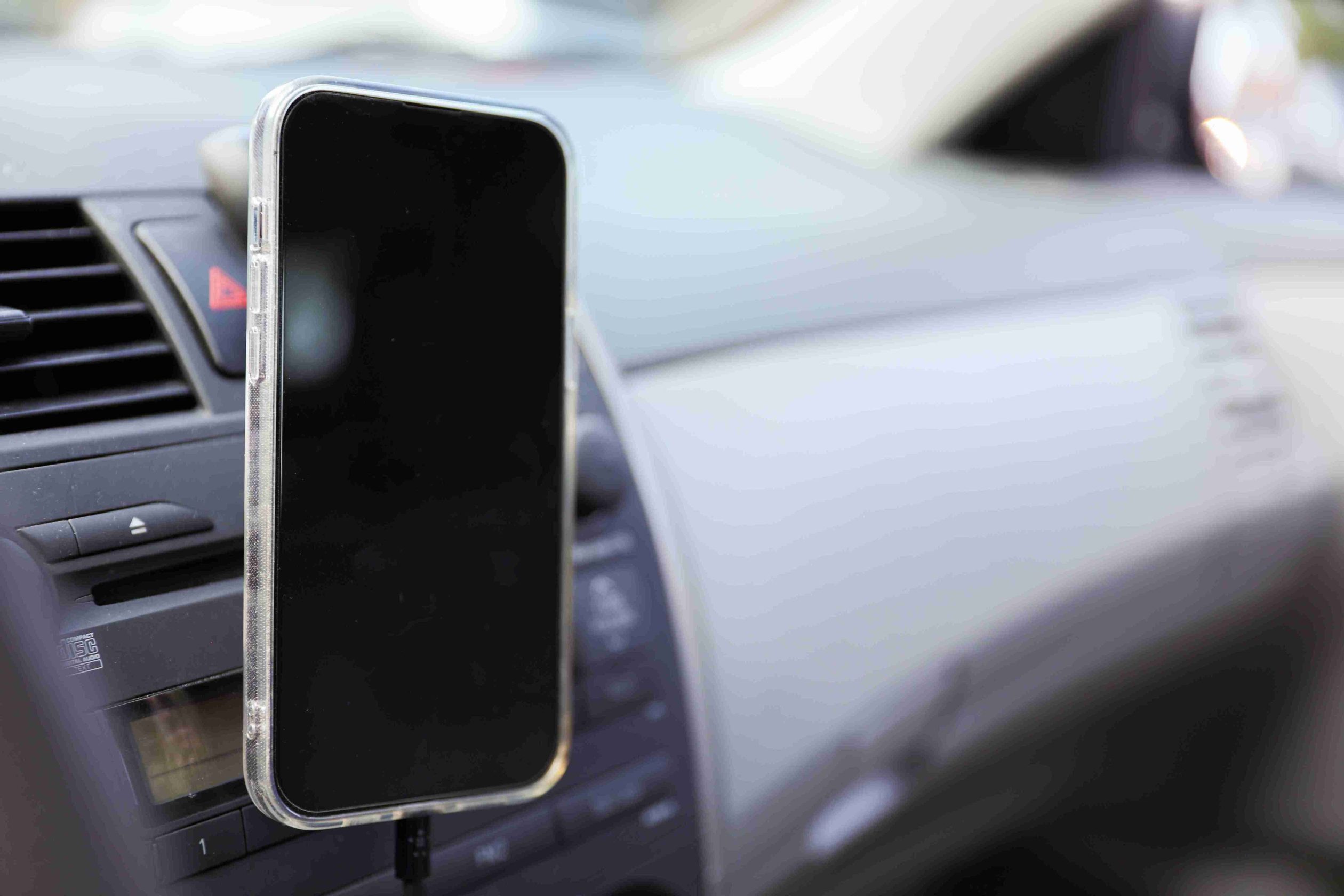 Car air vent phone mount in use with a blank smartphone, automotive interior lifestyle shot.