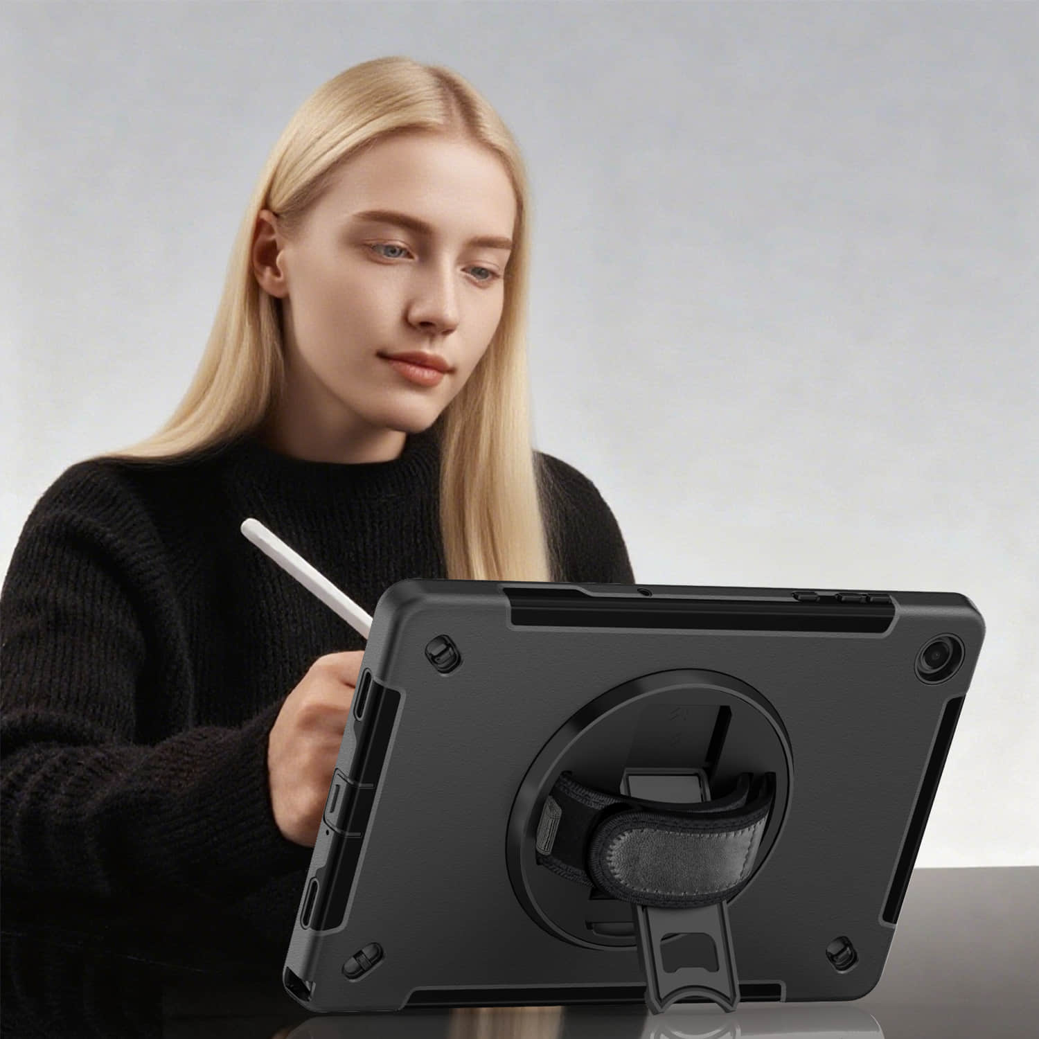 Woman using stylus on tablet protected by rugged heavy-duty protective case with kickstand and hand strap