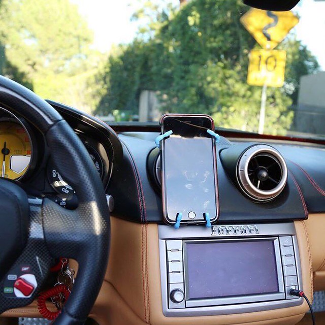 Car phone mount installation photo, dashboard/air vent mounting, driver's seat view.